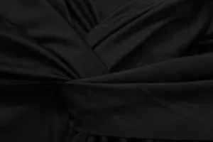 Macro shot of the elegant pleated knot detail on a black sleeveless evening dress.