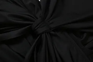 Detailed close-up showing central knot and radiating pleats on black bodycon dress