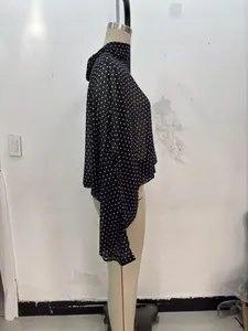 Seitenansicht einer schwarzen Polka-Dot-Bluse mit asymmetrischen Drapierungen.