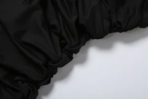 Macro view showing the ruched pleating detail and soft texture of black dress fabric