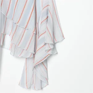 Dettaglio di un top a righe velato con eleganti bordi a volant e design con fiocco.