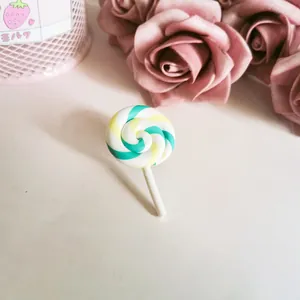 Close-up of a sweet polymer clay lollipop brooch with a teal and yellow spiral