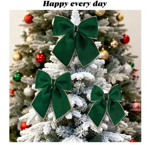 Close-up of green velvet Christmas bows with gold trim on a white flocked tree