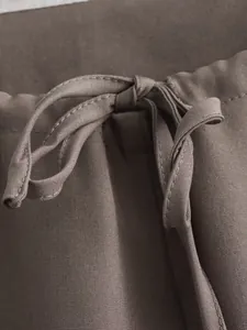 Gros plan sur le cordon de serrage réglable en tissu d'un pantalon marron minimaliste