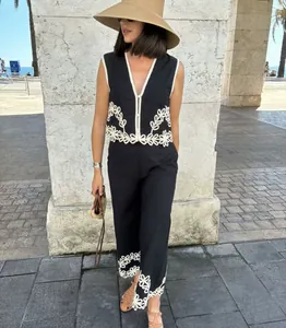 Vista dettagliata di set gilet e pantaloni neri con ricamo floreale bianco su modella.