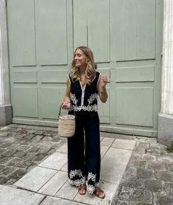 Dettaglio dell'outfit composto da gilet ricamato nero e pantaloni larghi da donna.