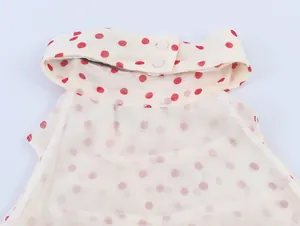 Nahaufnahme eines cremefarbenen Georgette-Haltertops mit roten Punkten und Knopfkragen
