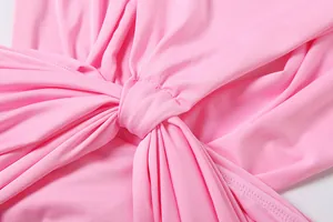 Close-up of the elegant central knot and pleated fabric detail on the pink dress