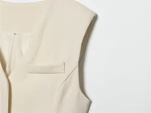 Detailed macro view of beige women's vest featuring V-neck and decorative flap pocket