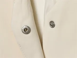 Close-up detail of hidden metal snap button closure on a beige garment