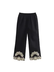 Eleganti pantaloni neri con delicati ricami in pizzo floreale crema sull'orlo