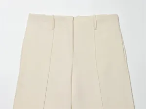 Detailed view of the high-waist hidden button closure on beige tailored shorts for women