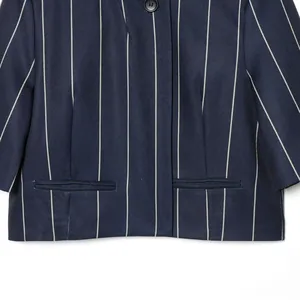 Detailed view of navy blue pinstripe cropped jacket with elegant welt pockets