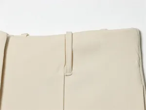 Close-up detail of the beige shorts waistband featuring belt loops and hidden closure