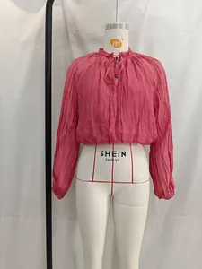 Detailed view of a pink pleated long sleeve crop top displayed on a white mannequin.