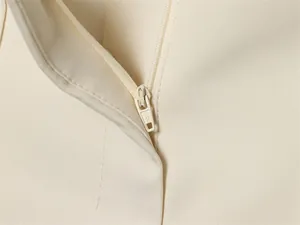 Detailed close-up of a smooth hidden zipper on cream women's vest and shorts set