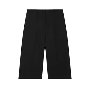 Detail of black high-waisted wide-leg shorts with hidden button closure and pleats.