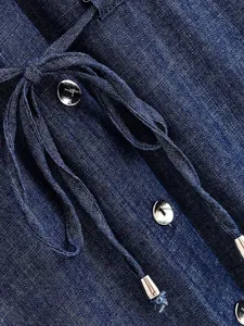 Macro detail of navy blue denim texture featuring silver buttons and drawstring metal tips