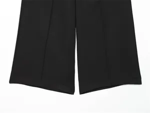 Close-up detail of the wide leg hem on a pair of elegant black tailored shorts.
