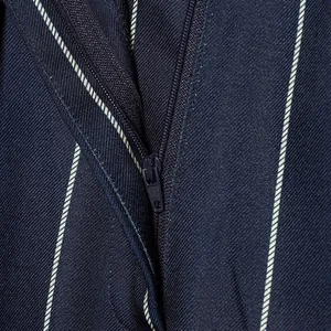 Detailed view of the functional zipper on navy blue pinstripe suit trousers fabric