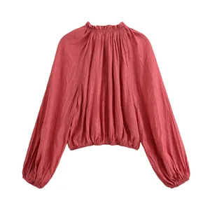 Detailed view of a rust red pleated long-sleeve crop top with elasticated hem and neck.