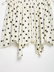 Detalle de falda midi blanca de lunares negros con dobladillo asimétrico fluido