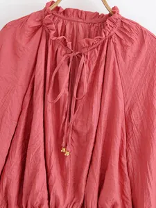 Close-up of pink crinkle long sleeve blouse with ruffled collar and tie neck detail.