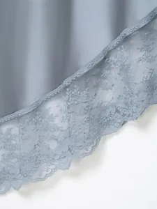 Primer plano del elegante dobladillo de falda de satén azul claro con encaje floral.