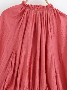 Detailed view of elegant crinkled fabric texture on coral ruffled neckline blouse