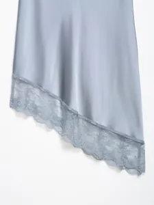 Detalle de falda asimétrica de satén azul claro con un elegante ribete de encaje.