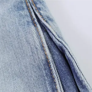 Detailed macro view showing quality yellow double-stitching on light blue denim jeans