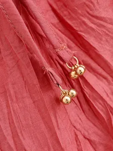 Close-up of coral red wrinkled fabric with elegant gold bead drawstring charms.