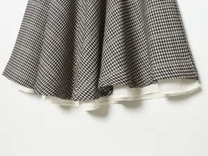 Detailed macro view of a vintage plaid skirt hem featuring white lining fabrics