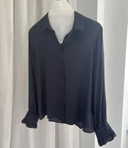 Detailed view of black satin shirt featuring island silk fabric and ruffled cuffs