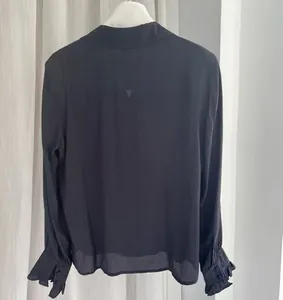 Back view of a satin silk blouse with ruffled cuffs and subtle textures