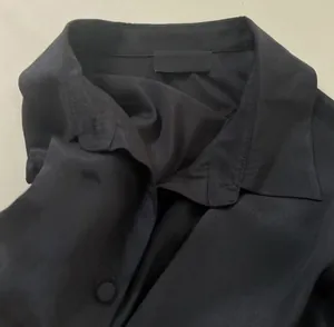 Detailed close-up of a black satin silk shirt collar with soft texture and crinkle
