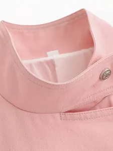 Macro view of a sweet pink stand collar jacket featuring an ornate metal button detail