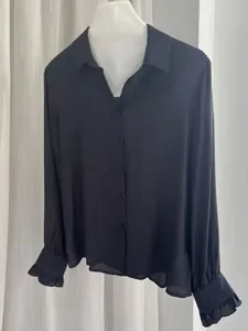 Elegant black satin silk long-sleeved blouse with stylish ruffled cuffs on white mannequin