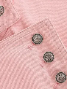Detailed view of metallic crest buttons on pink twill jacket collar