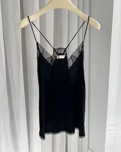 Close-up detail of a black rhinestone slip dress featuring delicate lace trim and cross straps