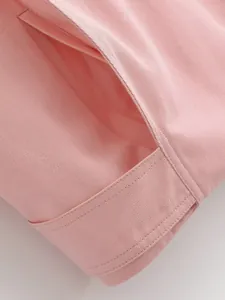 Close-up detail of a pink twill jacket showing the pocket and fine stitching quality.