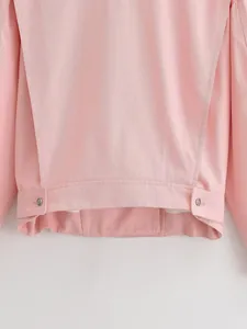 Detailed view of the hem and metallic button accents on a pink stand collar jacket