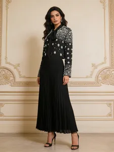 Detailed view of elegant black long sleeve top with pearl beads and pleated skirt