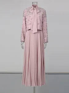 Close-up detail of elegant pink beaded jacket and pleated maxi skirt set on transparent mannequin