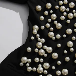 Détail rapproché des perles élégantes sur une robe blazer noire au design sophistiqué