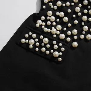 Vue détaillée de la broderie de perles blanches irrégulières sur le tissu noir d'une robe rétro