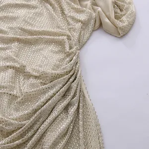 Detailed shot of sparkling silver rhinestones on elegant beige pleated fabric