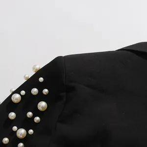 Gros plan de l'épaule d'un blazer noir avec des perles irrégulières élégantes