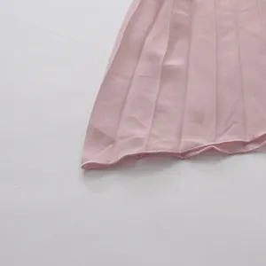 Close-up of pink pleated skirt hem showing fine fabric texture and neat stitching