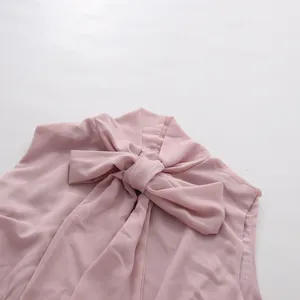 Detail shot of an elegant pink sleeveless top featuring a large soft bow at the neckline
